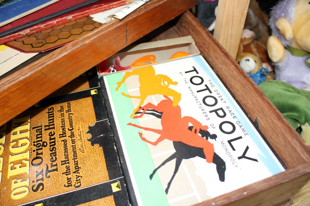 A quantity of assorted toys and games in a stacking three tier box